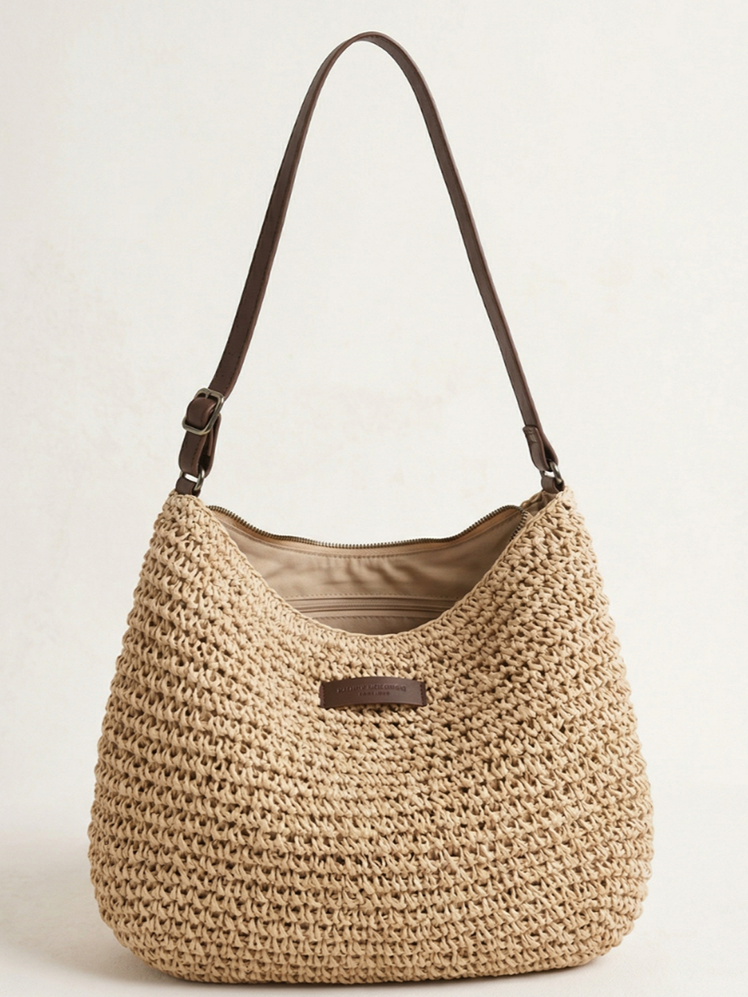 Bolso bandolera hobo trenzado beige con asa de cuero marrón y cierre rectangular.