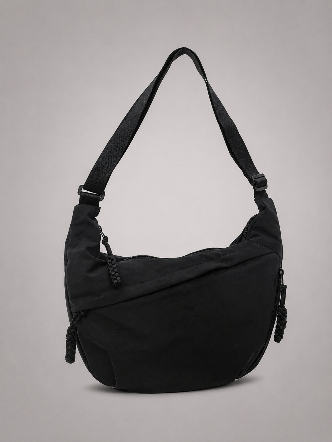 Bolso hombro negro con correa ajustable, cierre lateral y detalle frontal con borlas