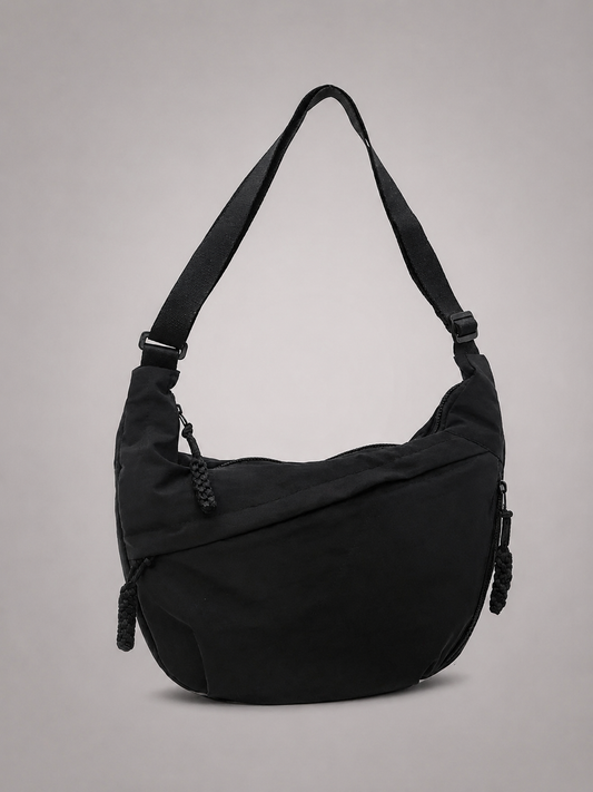 Bolso hombro negro con correa ajustable, cierre lateral y detalle frontal con borlas